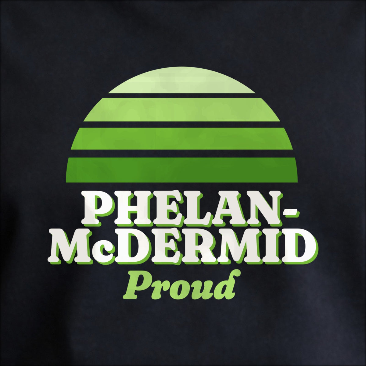 Close-up of the print on black: a striped half-sun in green above cream PHELAN-McDERMID lettering with “Proud” in script.