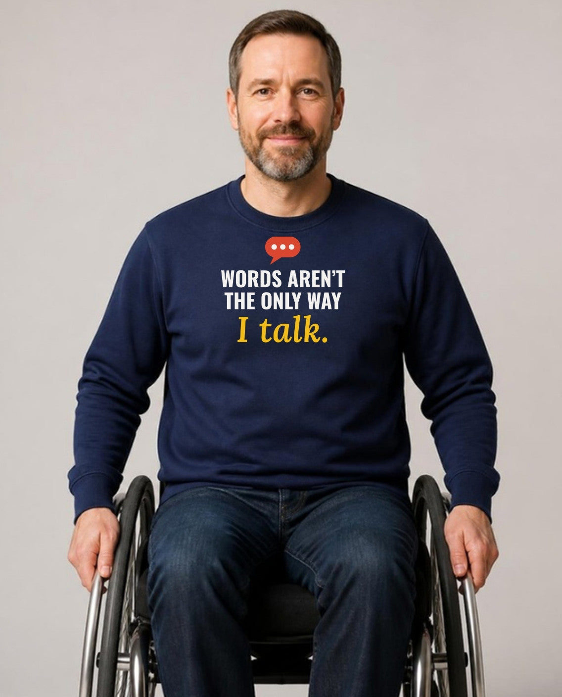 Man who uses a wheelchair, wearing the navy Words Aren’t the Only Way I Talk sweatshirt