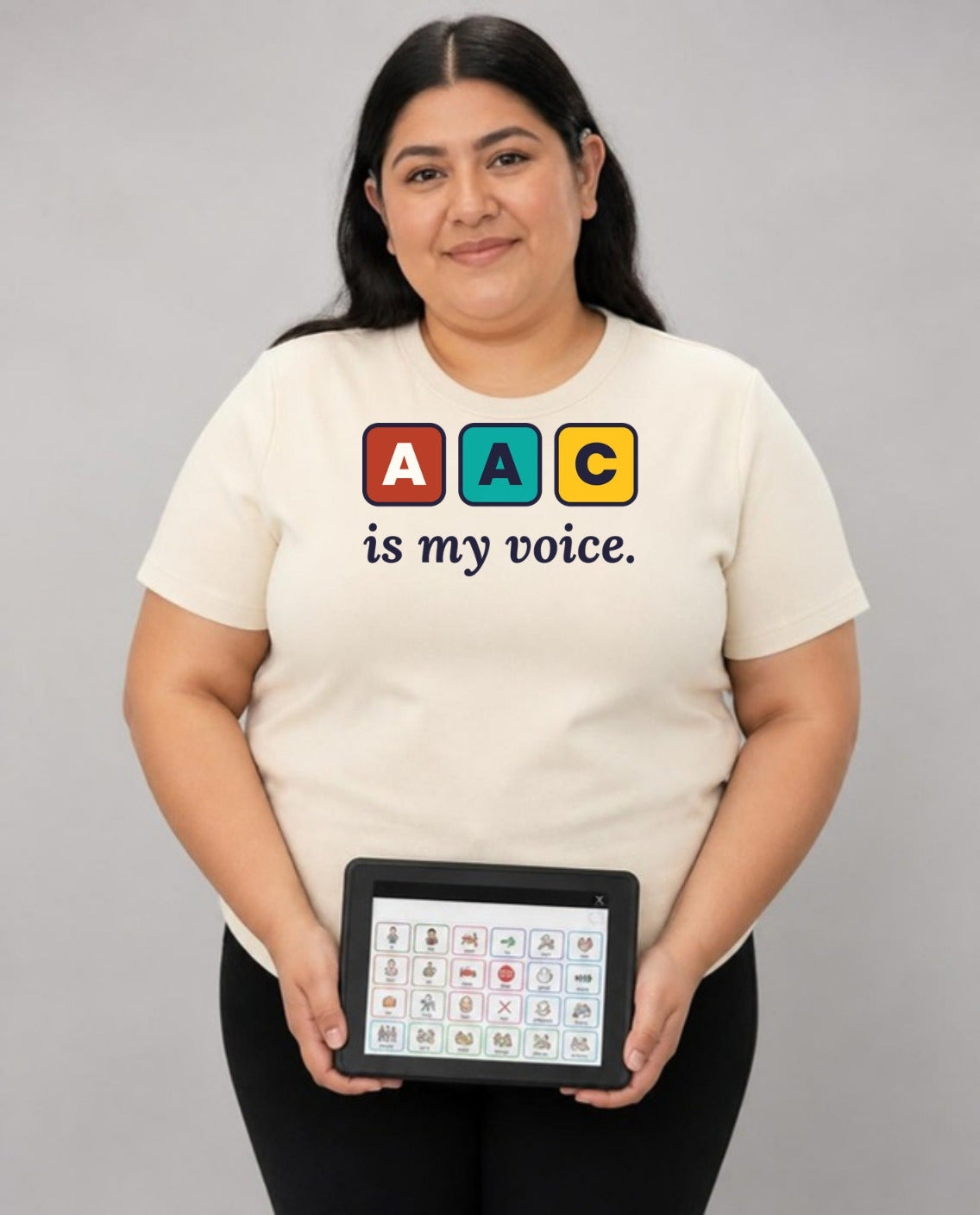Woman holding her AAC talker, wearing the AAC Is My Voice Adult Tee in Natural