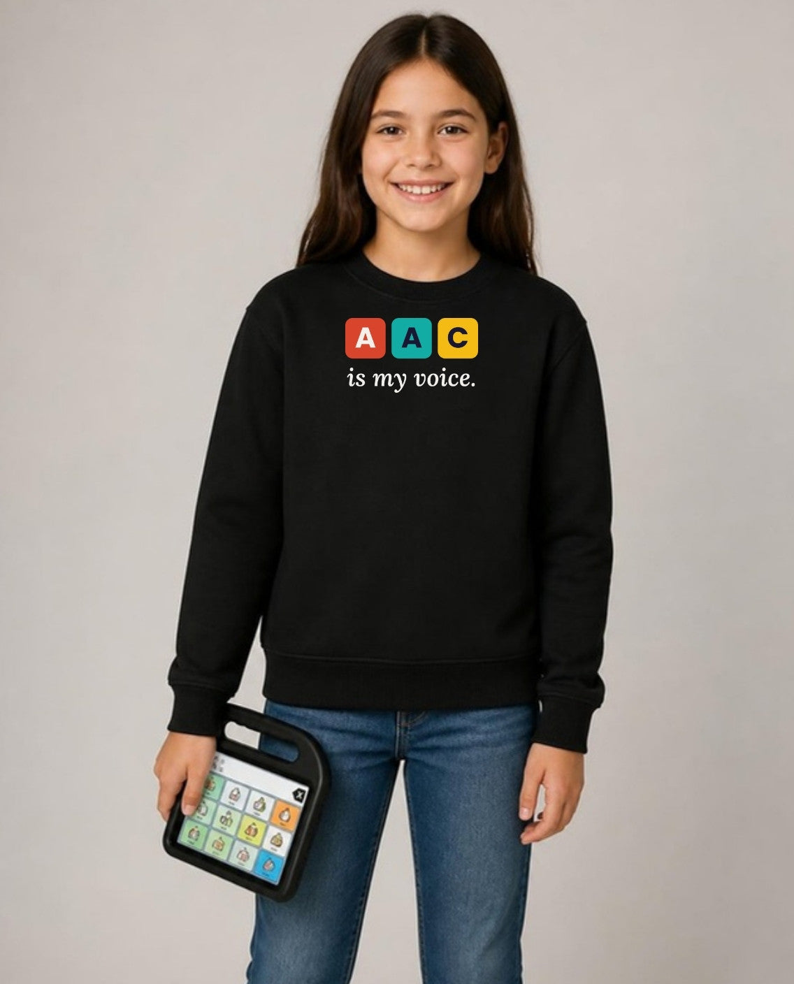 Girl holding her AAC talker, wearing the black AAC Is My Voice youth sweatshirt