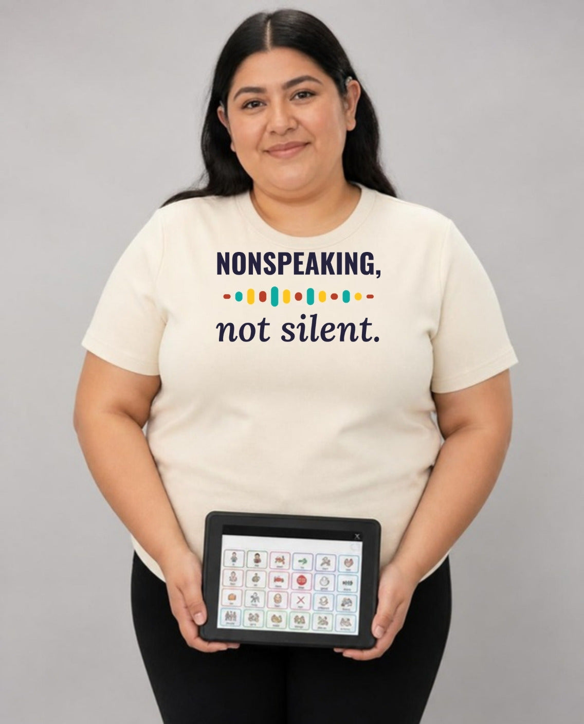 Woman holding her AAC talker, wearing the Nonspeaking, Not Silent Adult Tee in Natural