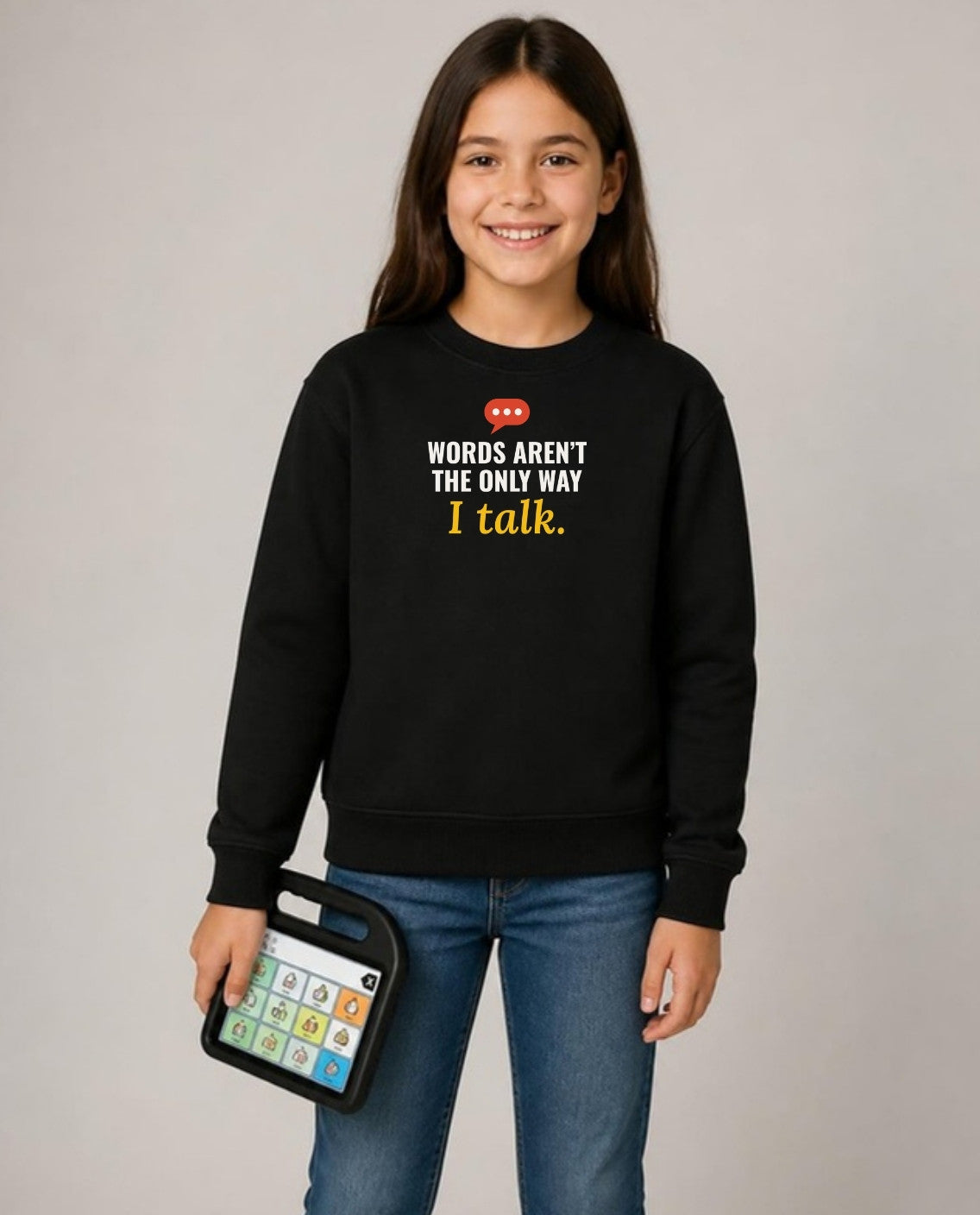 Girl holding her AAC talker, wearing the black Words Aren’t the Only Way I Talk youth sweatshirt