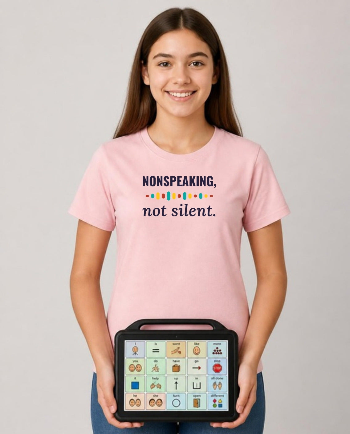 Teen holding her AAC talker wearing the Nonspeaking, Not Silent Adult Tee in Pink
