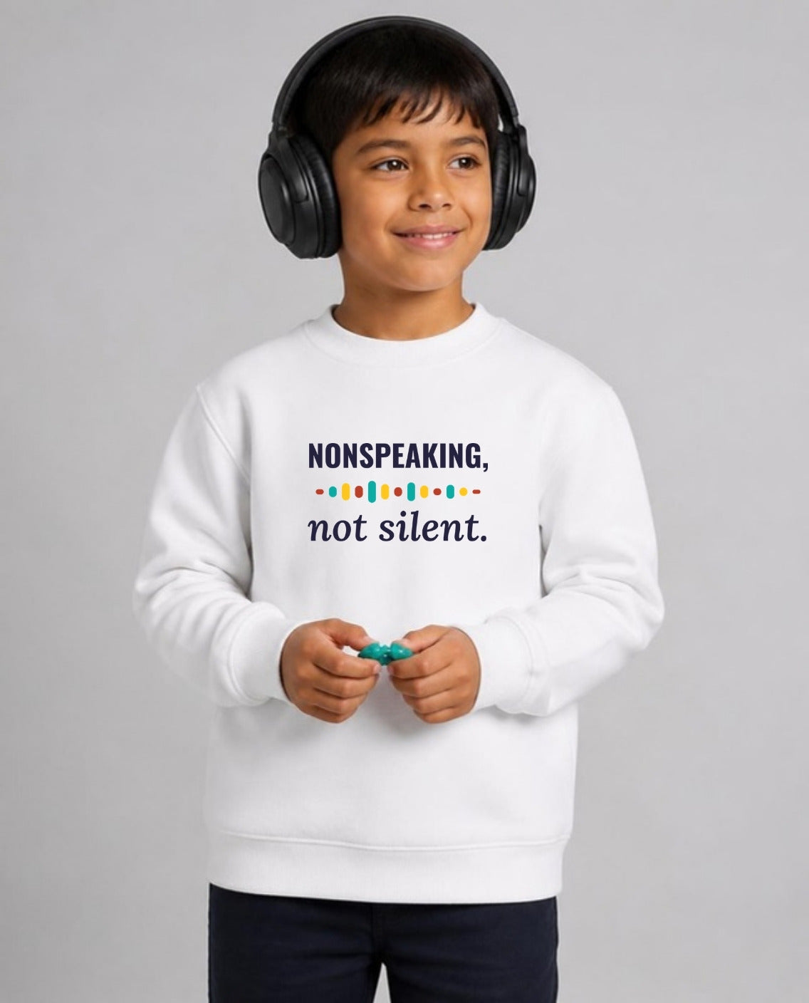 Autistic boy in noise-canceling headphones wearing the Nonspeaking, Not Silent Youth Sweatshirt in White