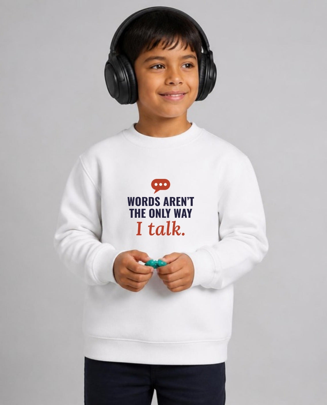 Autistic boy in noise-canceling headphones wearing the Words Aren’t the Only Way I Talk Youth Sweatshirt in White