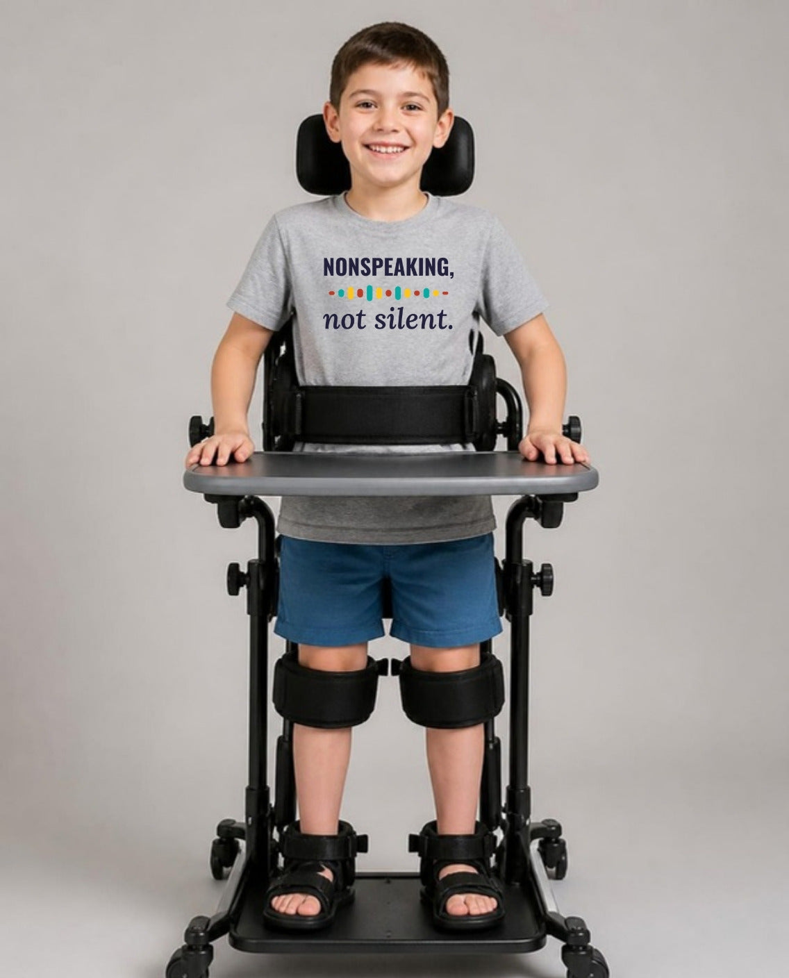 Boy standing in his stander wearing the Nonspeaking, Not Silent Youth Tee in Athletic Heather
