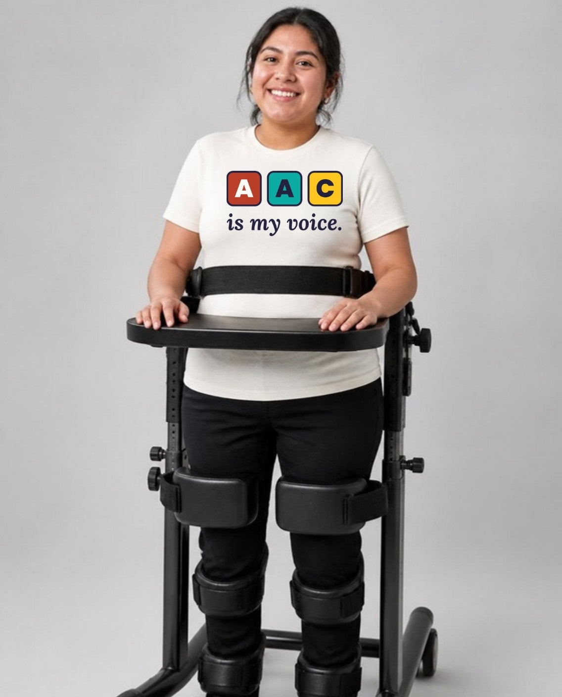 Woman standing in her stander wearing the AAC Is My Voice Adult Tee in Natural