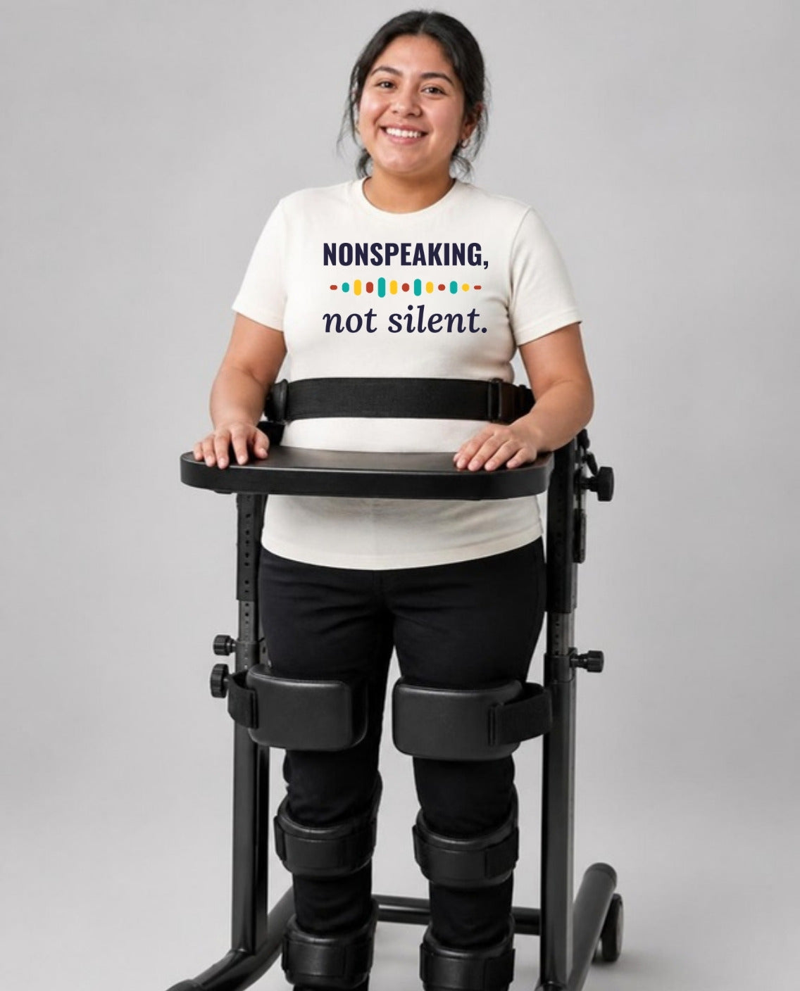 Woman standing in her stander wearing the Nonspeaking, Not Silent Adult Tee in Natural