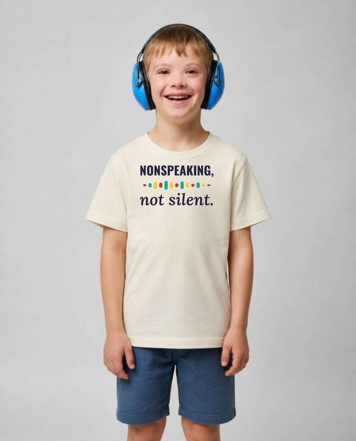 Boy with Down syndrome in noise-blocking headphones wearing the Nonspeaking, Not Silent Youth Tee in Natural