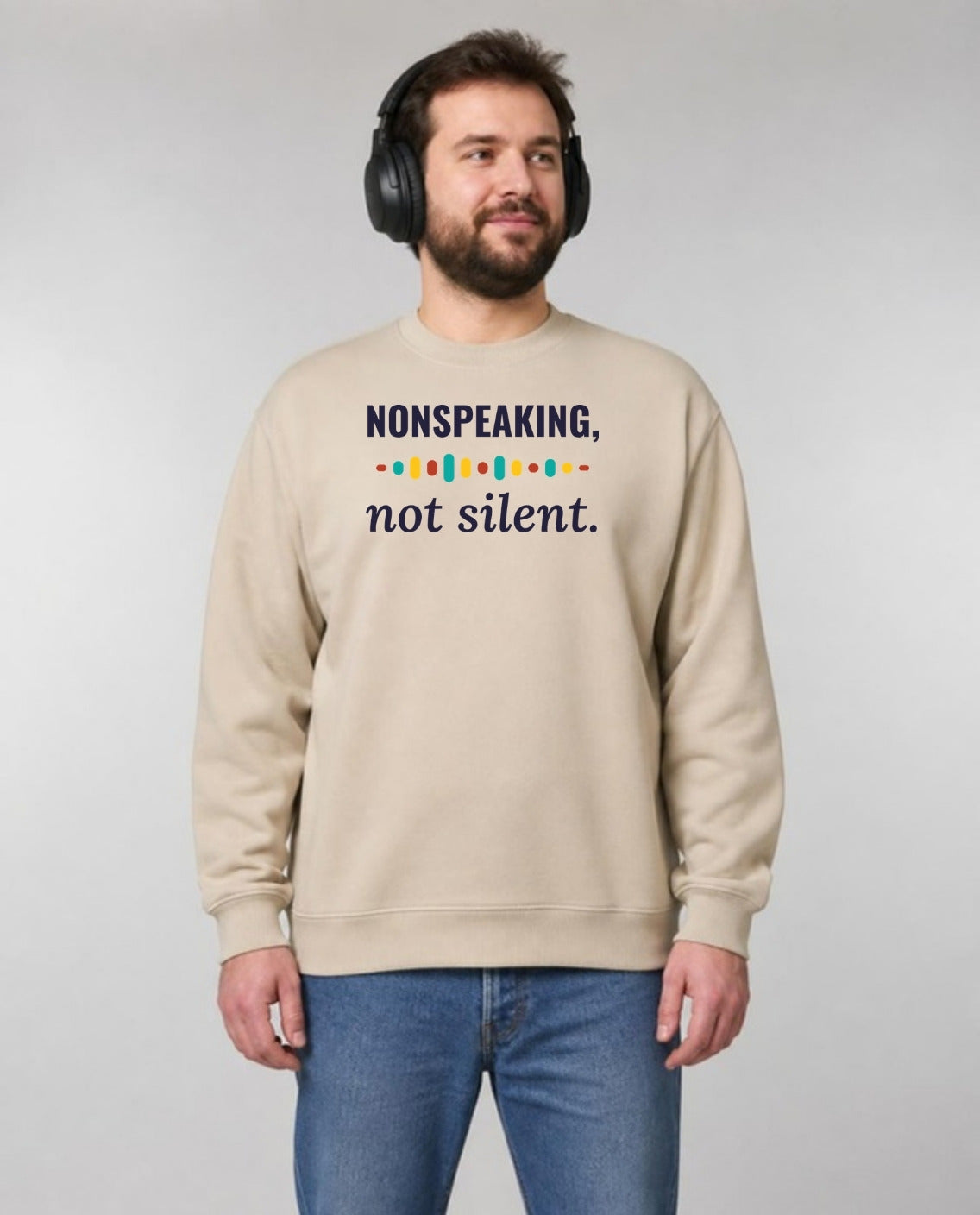 Autistic man in noise-blocking headphones wearing the Nonspeaking, Not Silent Adult Sweatshirt in Sand