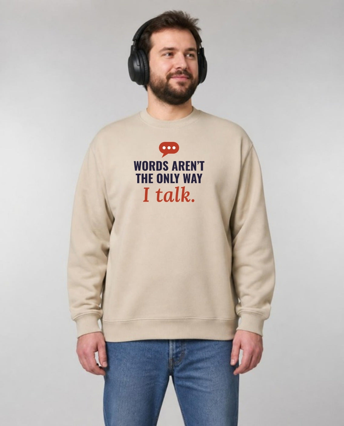Autistic man in noise-blocking headphones wearing the Words Aren’t the Only Way I Talk Adult Sweatshirt in Sand