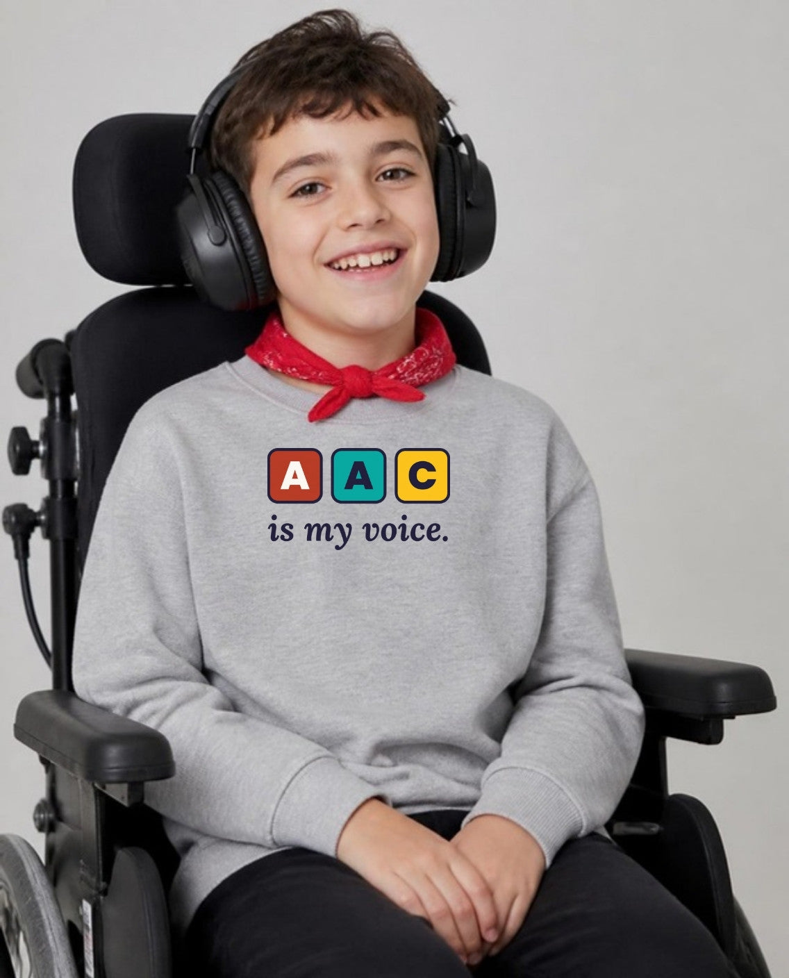 Boy with cerebral palsy in headphones, using a wheelchair, wearing the AAC Is My Voice Youth Sweatshirt in Sport Grey