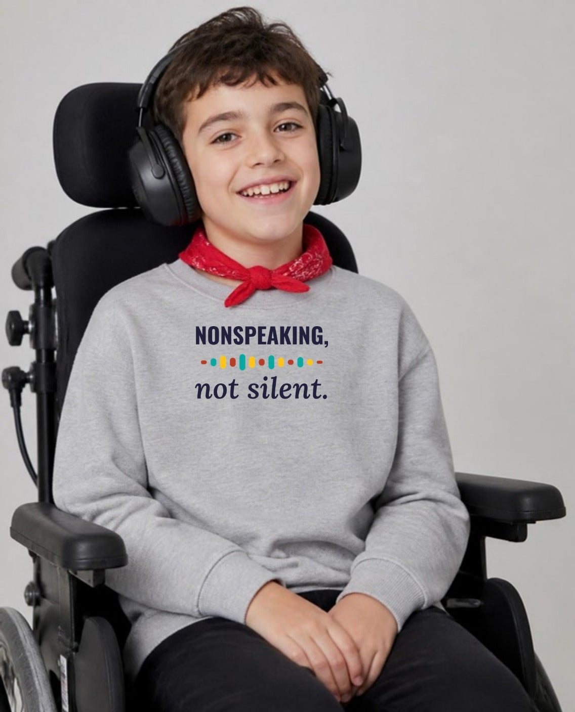 Boy with cerebral palsy in headphones, using a wheelchair, wearing the Nonspeaking, Not Silent Youth Sweatshirt in Sport Grey