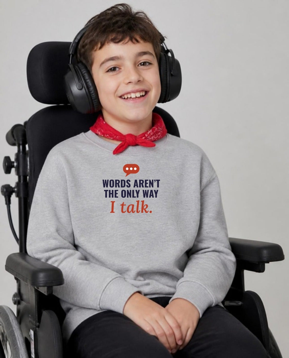 Boy with cerebral palsy in headphones, using a wheelchair, wearing the Words Aren’t the Only Way I Talk Youth Sweatshirt in Sport Grey