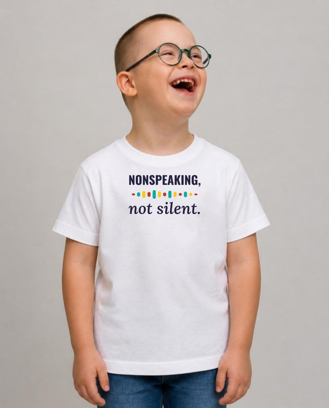 Boy in glasses laughing, looking up and away, wearing the Nonspeaking, Not Silent Youth Tee in White