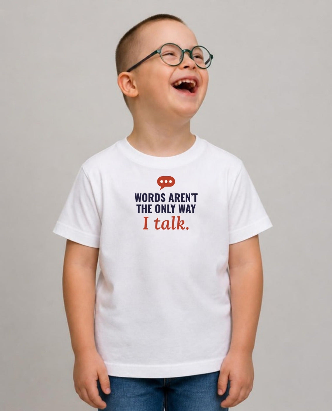 Boy in glasses laughing, looking up and away, wearing the Words Aren’t the Only Way I Talk Youth Tee in White
