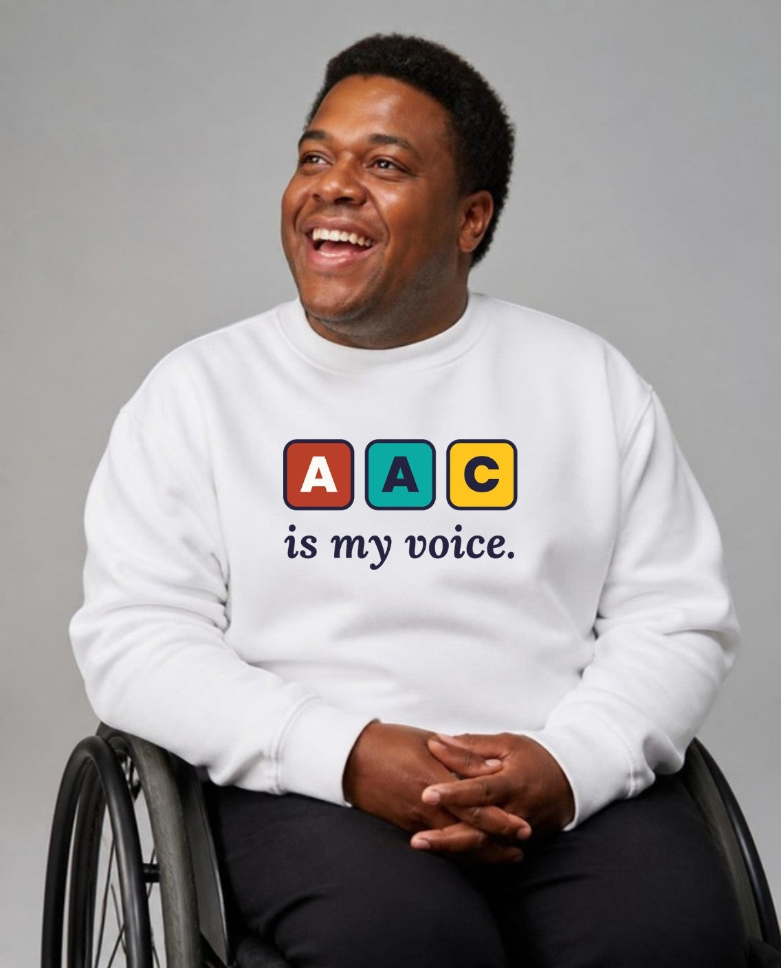 Man in his wheelchair smiling, looking up and away, wearing the AAC Is My Voice Adult Sweatshirt in White