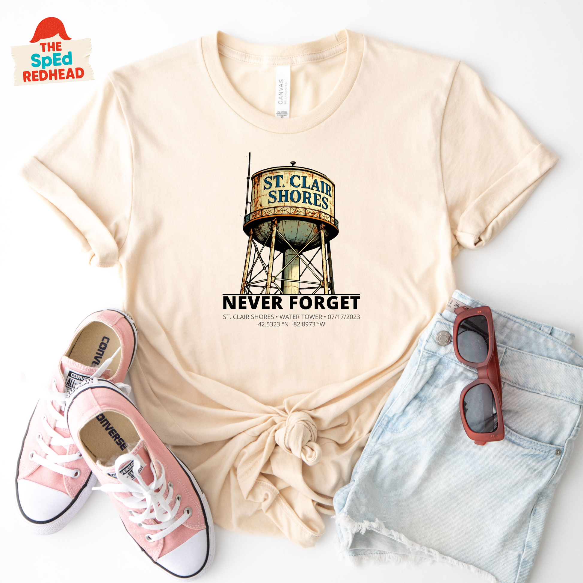 Beige t-shirt with water tower graphic, pink sneakers, denim shorts, and sunglasses on a white background.