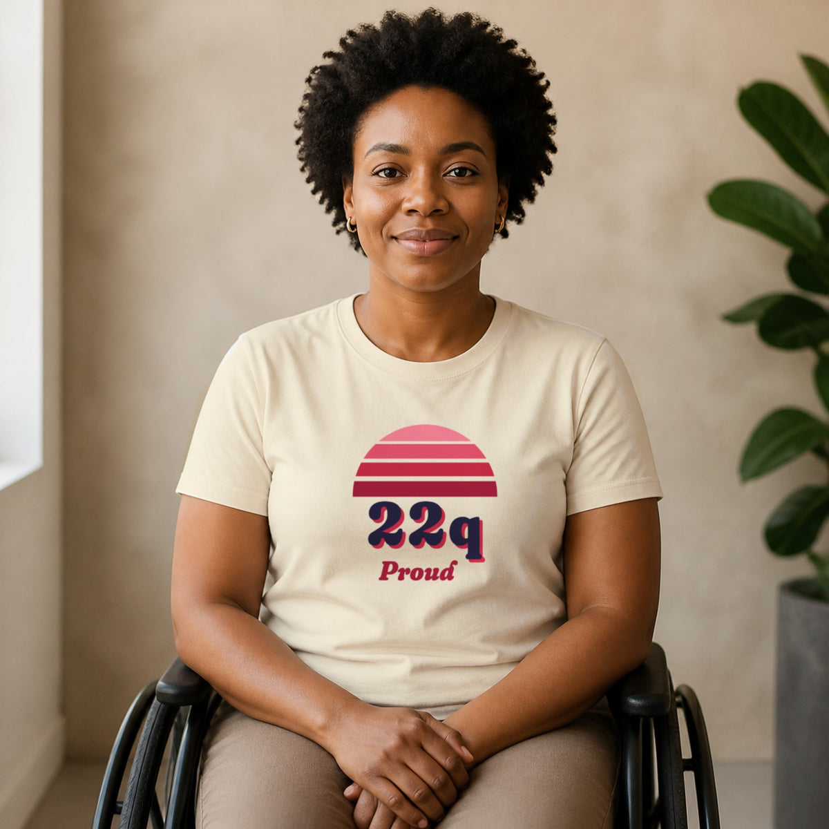 A woman seated in a wheelchair wears a natural-colored 22q Proud tee.