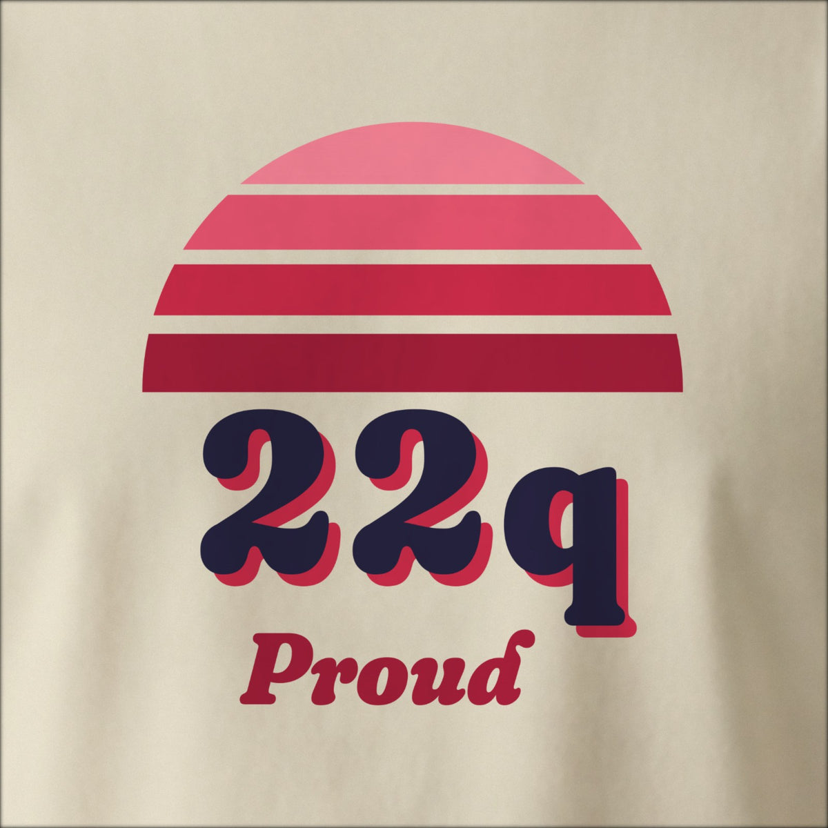 Close-up of the print on a natural tee: a striped half-sun in red above bold 22q lettering with “Proud” in script.