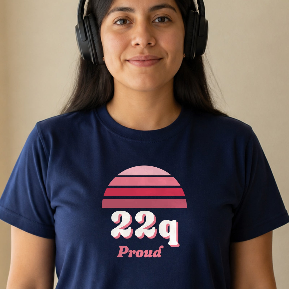 A woman in over-ear headphones wears a navy 22q Proud tee with a red striped retro sun.
