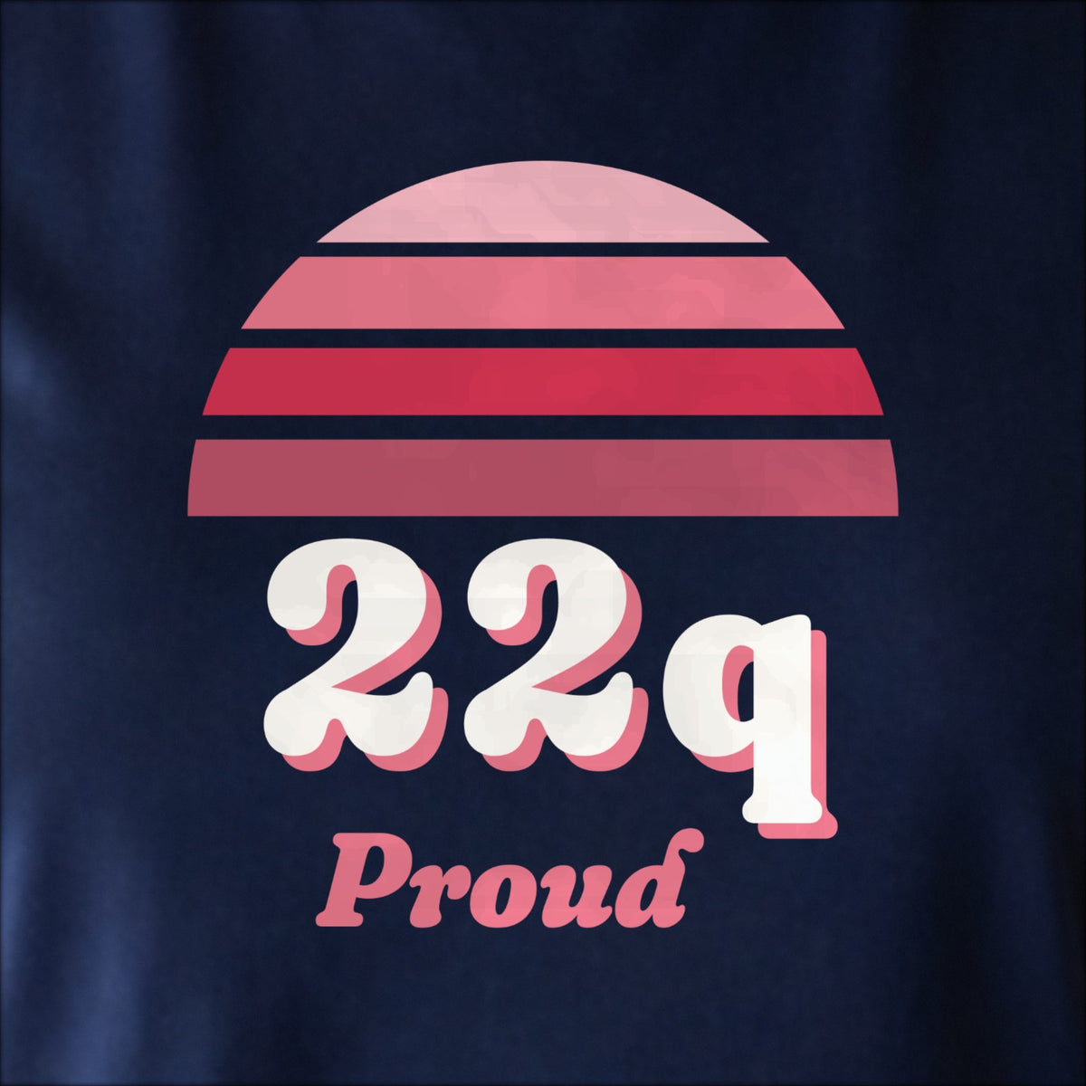 Close-up of the print on navy: a striped half-sun in red above cream 22q lettering with “Proud” in script.