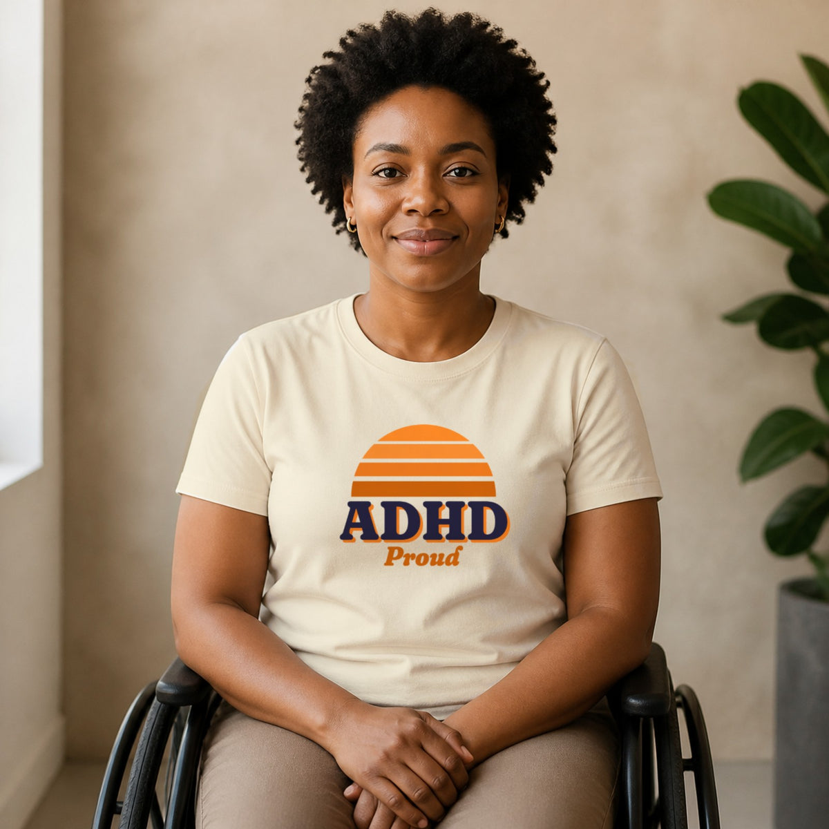 A woman seated in a wheelchair wears a natural-colored ADHD Proud tee.