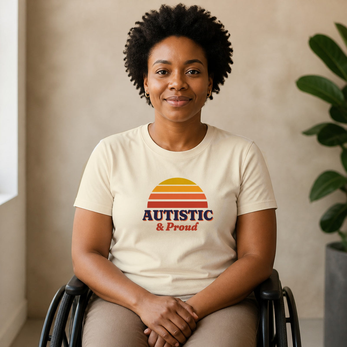 A woman seated in a wheelchair wears a natural-colored Autistic & Proud tee.