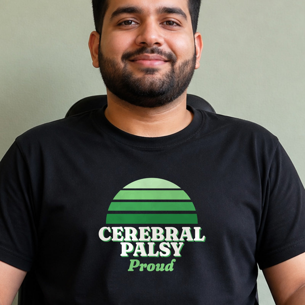 A man wears a black Cerebral Palsy Proud tee with a green striped retro sun.