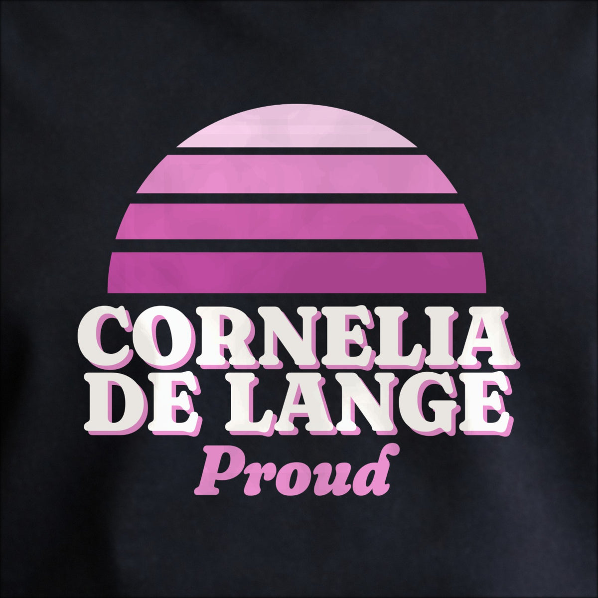 Close-up of the print on black: a striped half-sun in purple above cream CORNELIA DE LANGE lettering with “Proud” in script.