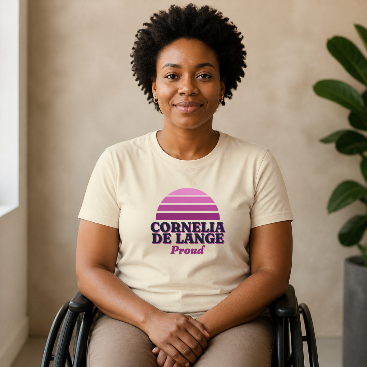 A woman seated in a wheelchair wears a natural-colored Cornelia de Lange Proud tee.
