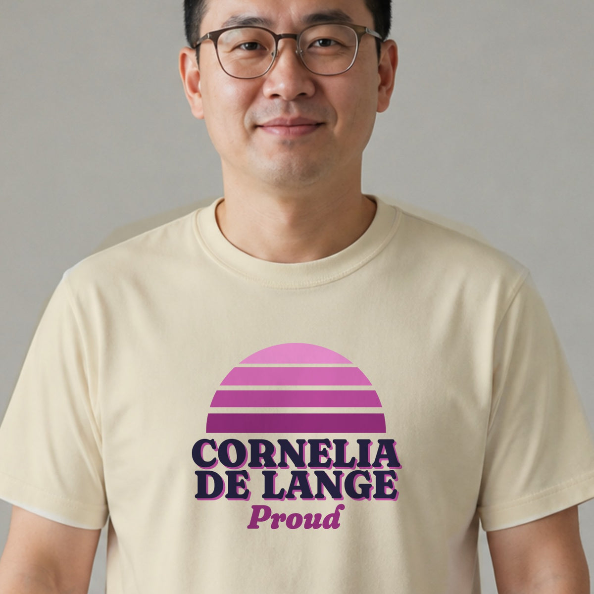 A man in glasses wears a natural-colored Cornelia de Lange Proud tee with a purple striped retro sun.