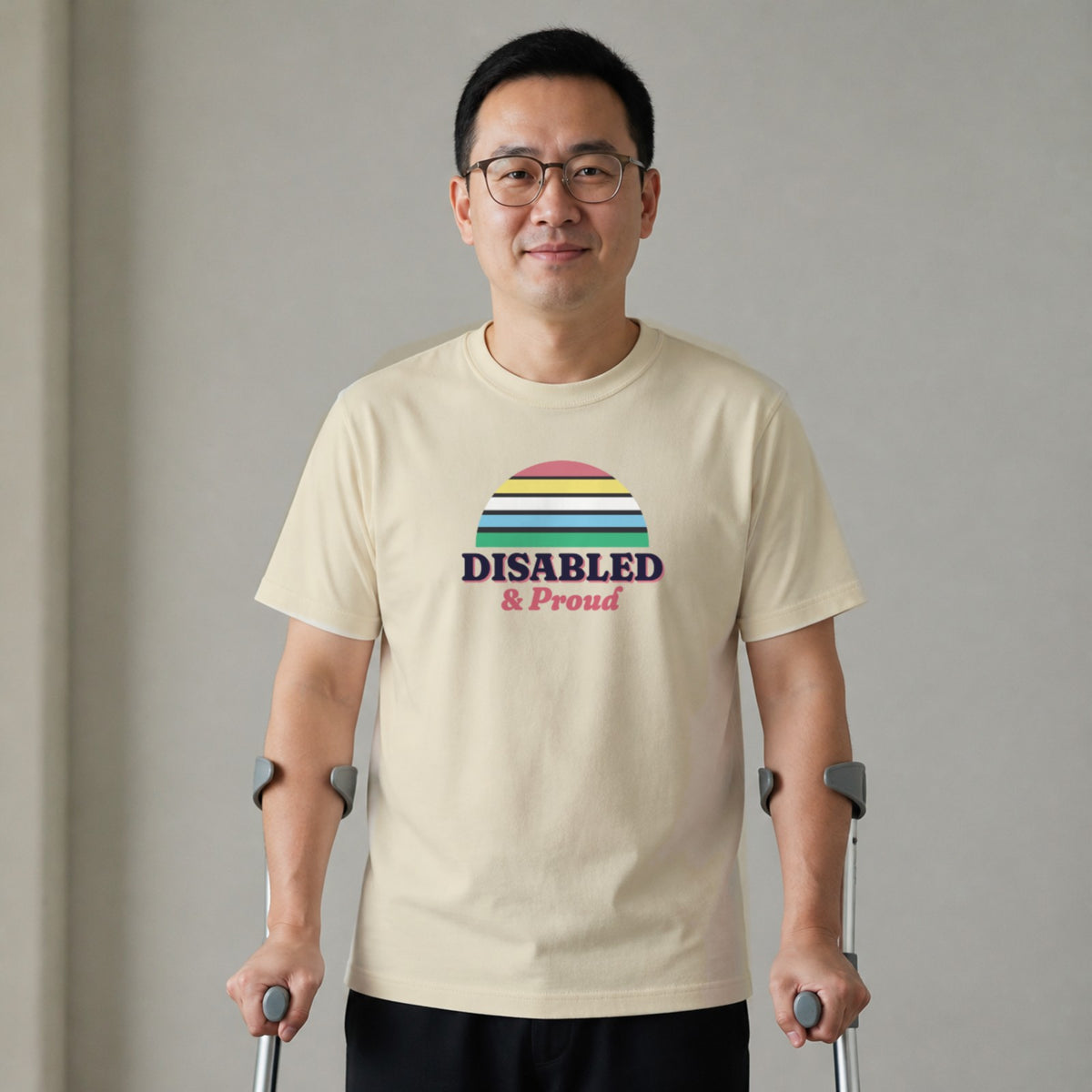 A man standing with two forearm crutches wears a natural-colored Disabled & Proud tee.