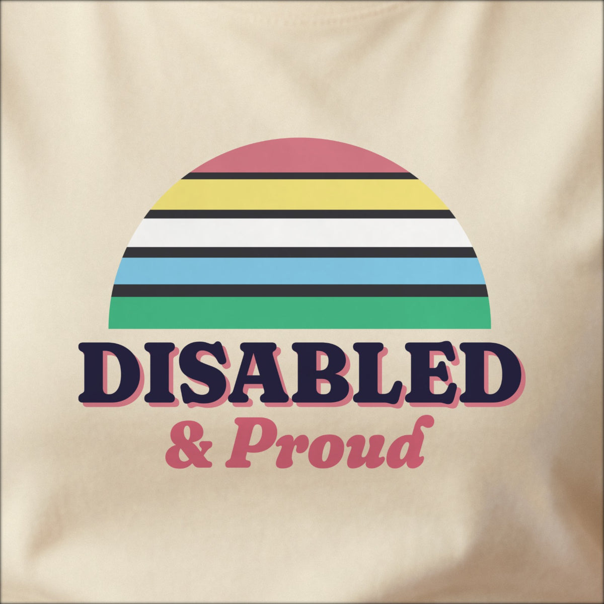 Close-up of the print on a natural tee: a five-stripe half-sun in the Disability Pride Flag colors, with charcoal lines between the stripes, above bold DISABLED lettering with “& Proud” in script.
