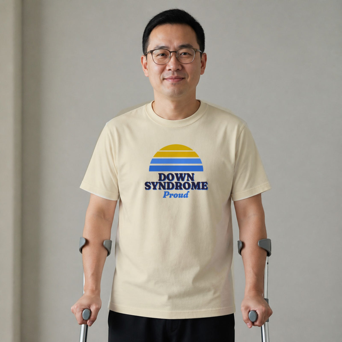 A man standing with two forearm crutches wears a natural-colored Down syndrome Proud tee.