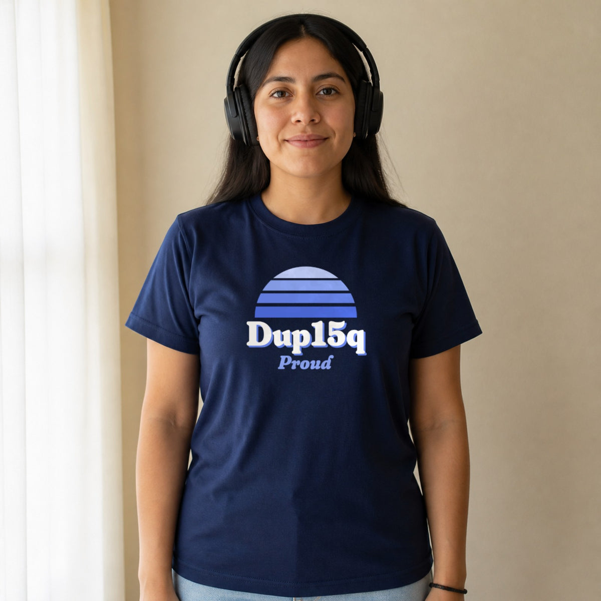 A woman in over-ear headphones wears a navy Dup15q Proud tee.