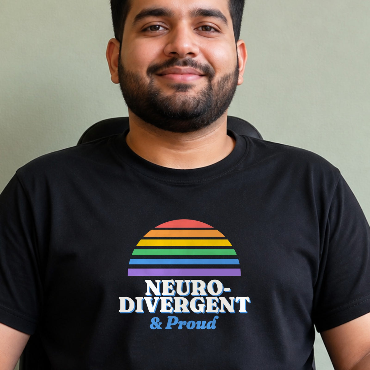 A man wears a black Neurodivergent & Proud tee with a rainbow striped retro sun.