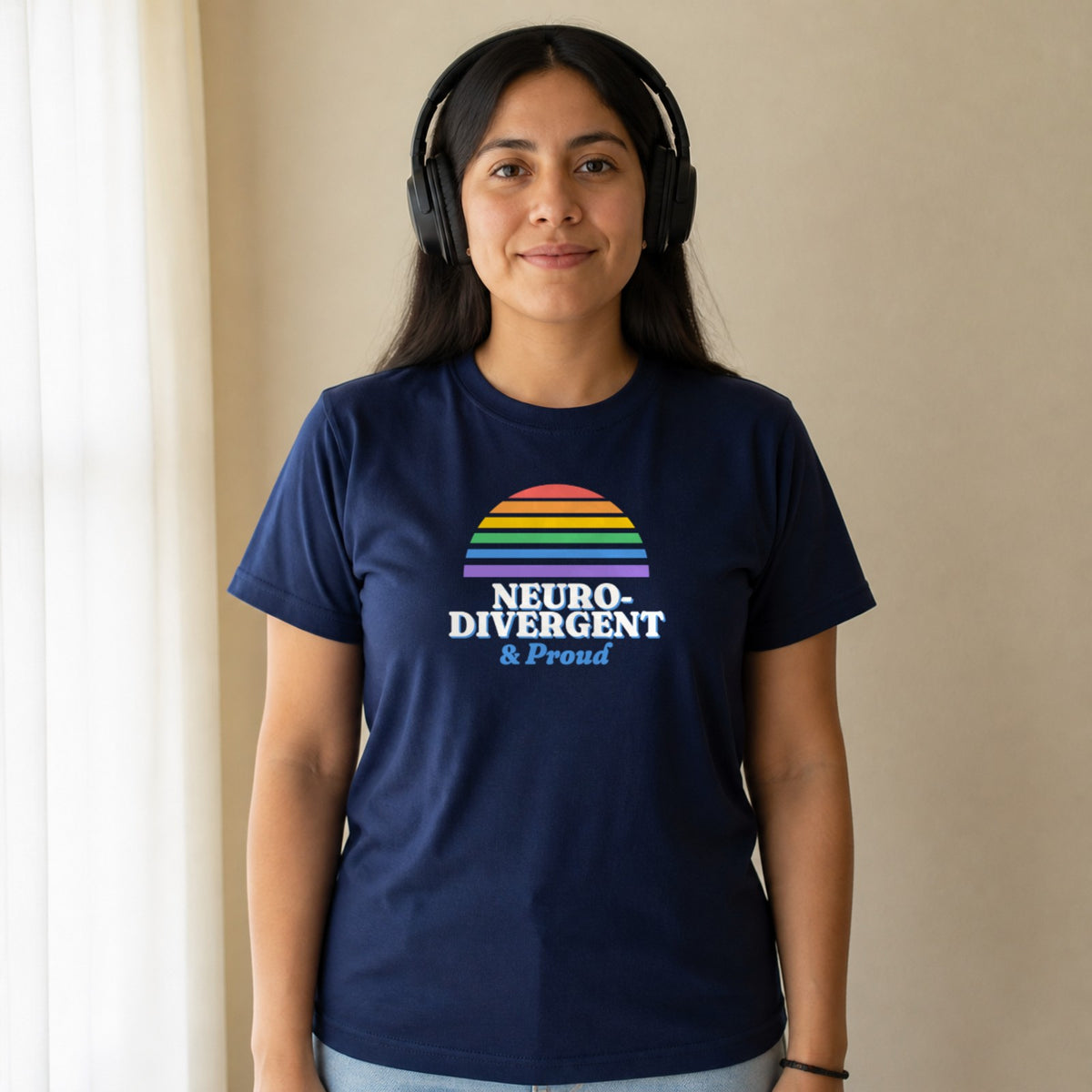 A woman in over-ear headphones wears a navy Neurodivergent & Proud tee.