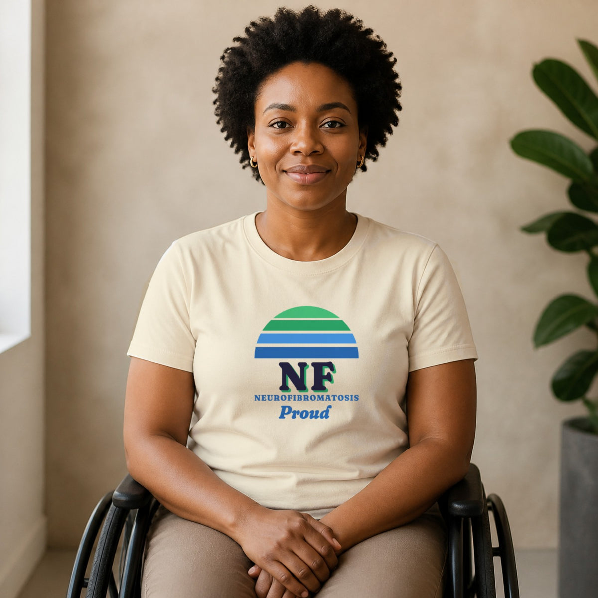A woman seated in a wheelchair wears a natural-colored NF Proud tee.