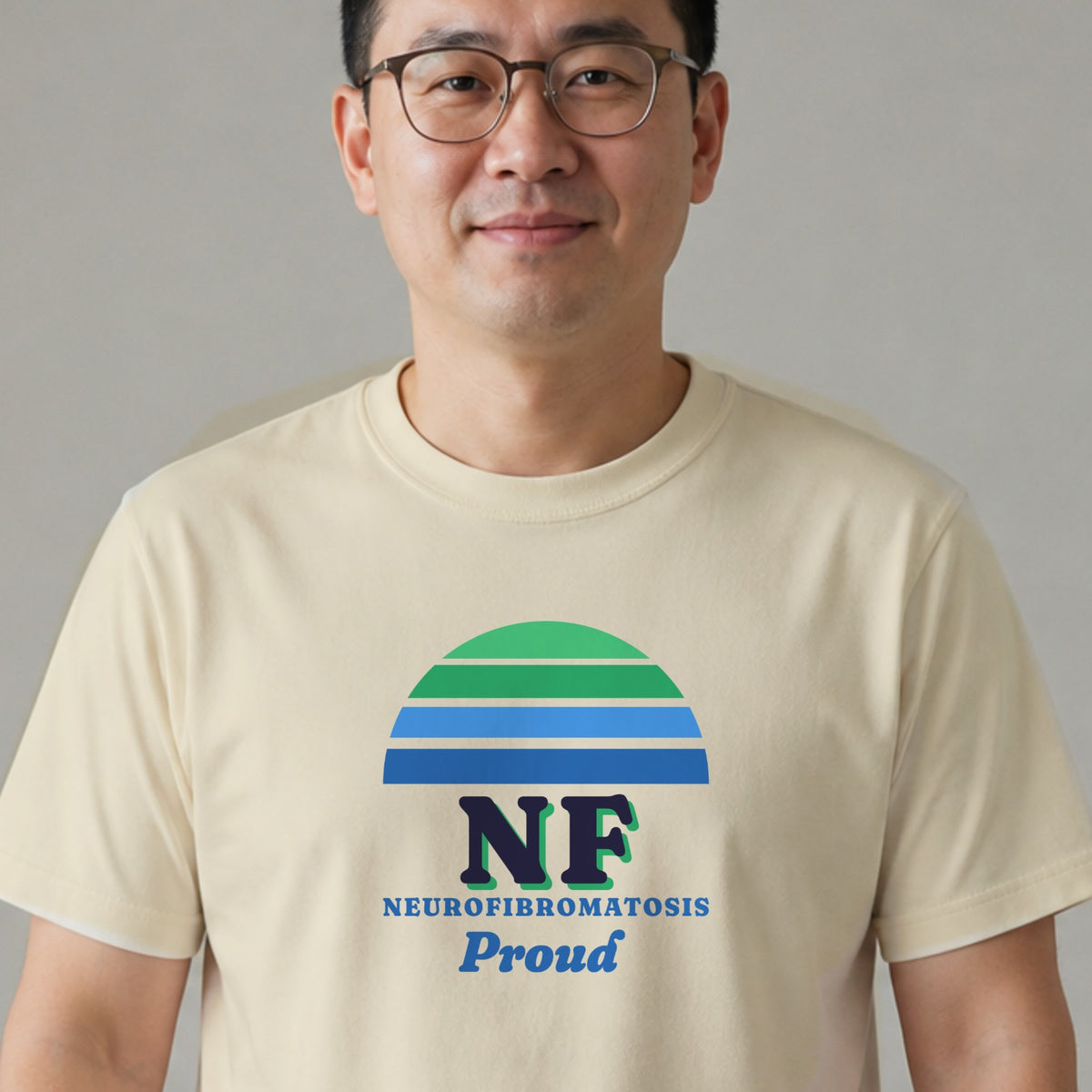 A man in glasses wears a natural-colored NF Proud tee with a green and blue striped retro sun.