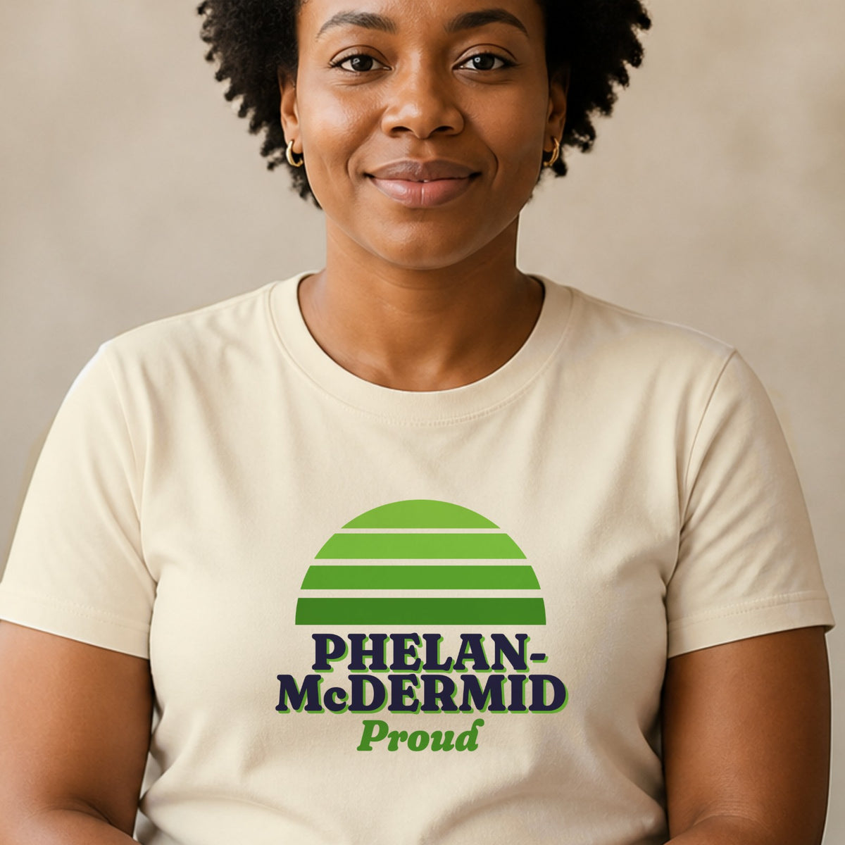 A woman wears a natural-colored Phelan-McDermid Proud tee with a green striped retro sun.