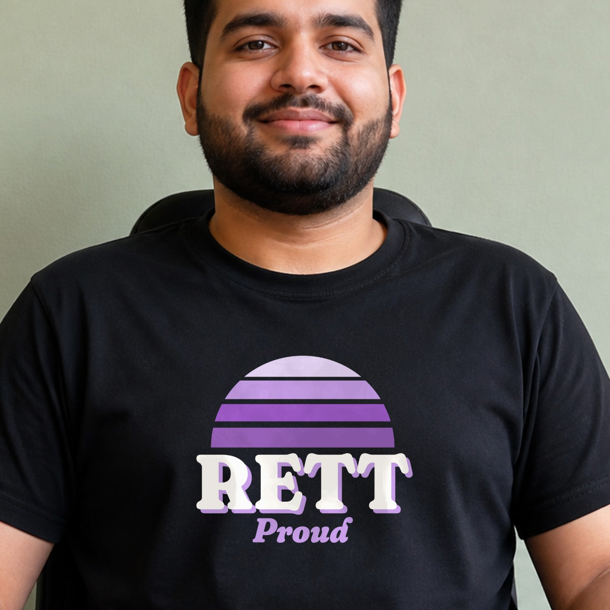 A man wears a black Rett Proud tee with a purple striped retro sun.