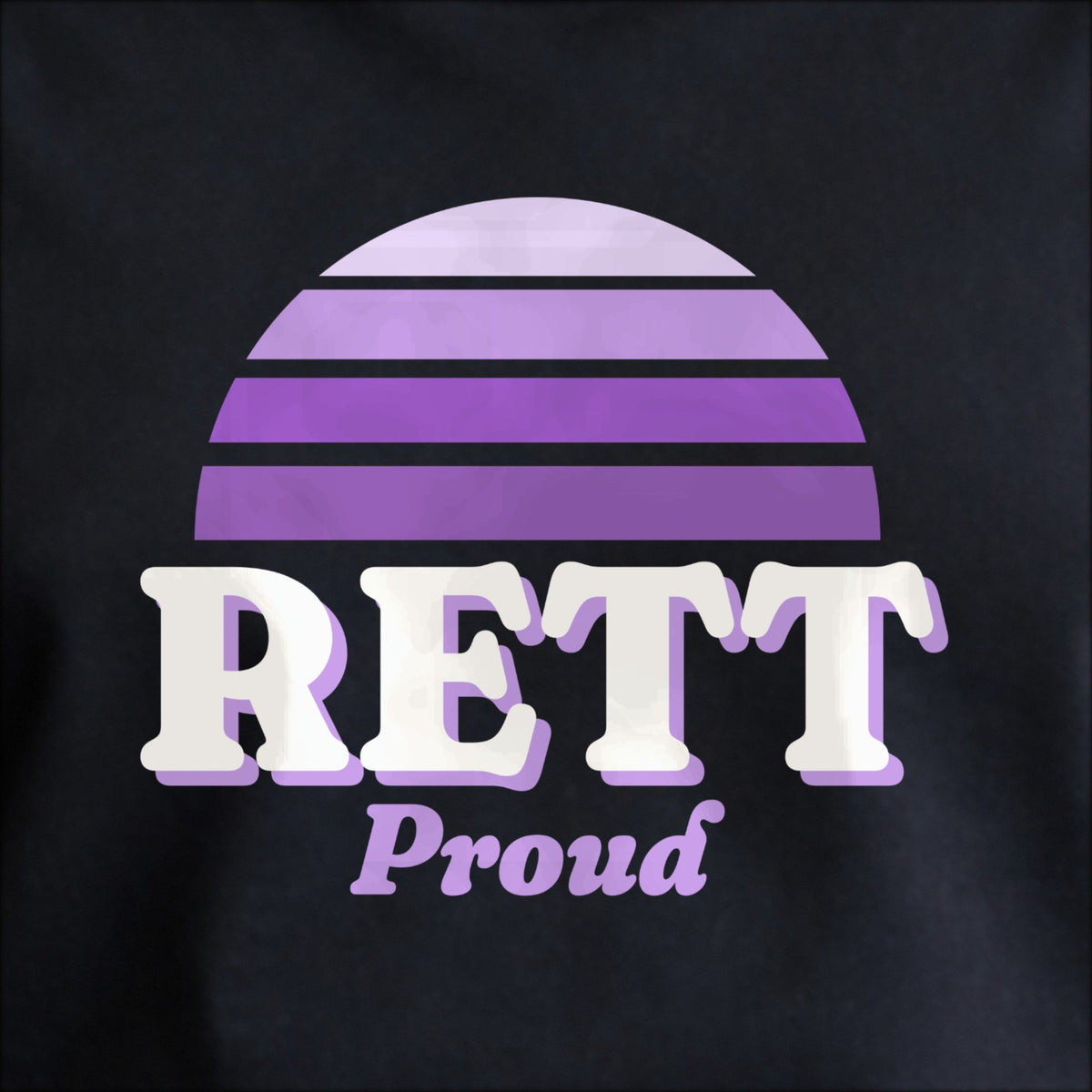 Close-up of the print on black: a striped half-sun in purple above cream RETT lettering with “Proud” in script.