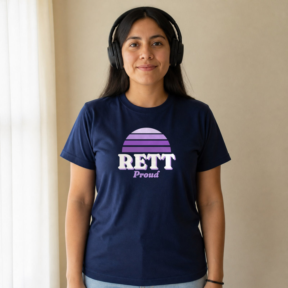 A woman in over-ear headphones wears a navy Rett Proud tee.
