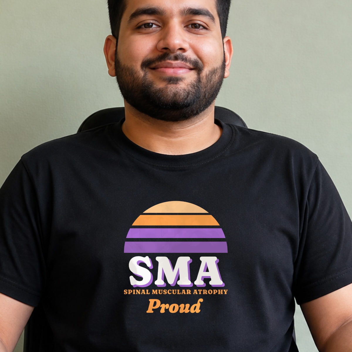 A man wears a black SMA Proud tee with an orange and purple striped retro sun.