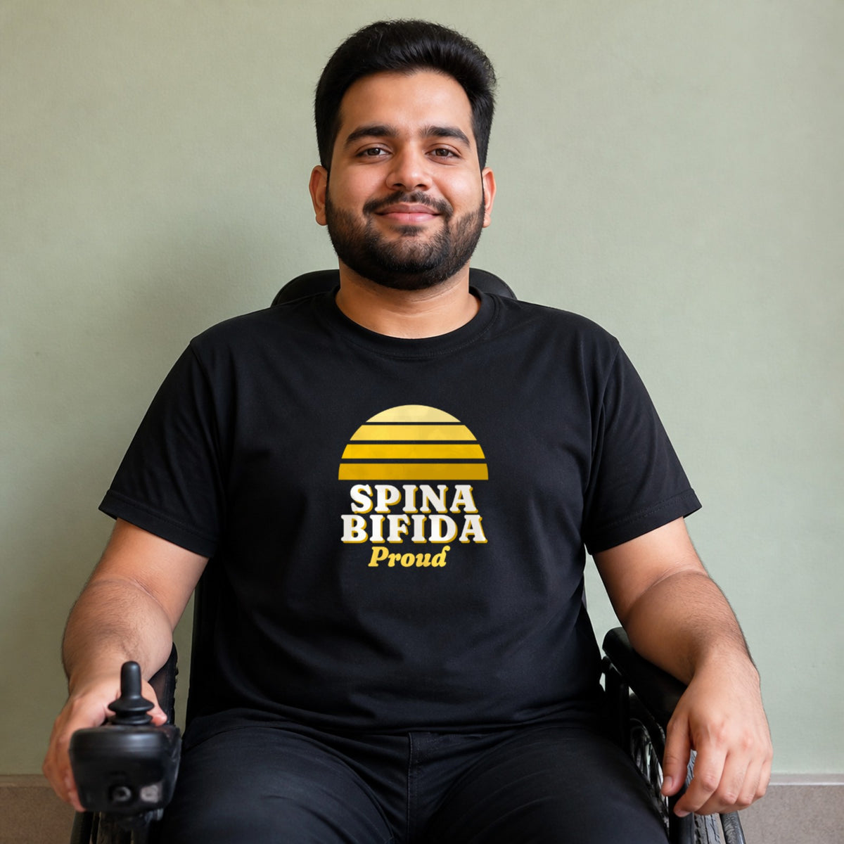 A man seated in a power wheelchair wears a black Spina Bifida Proud tee.