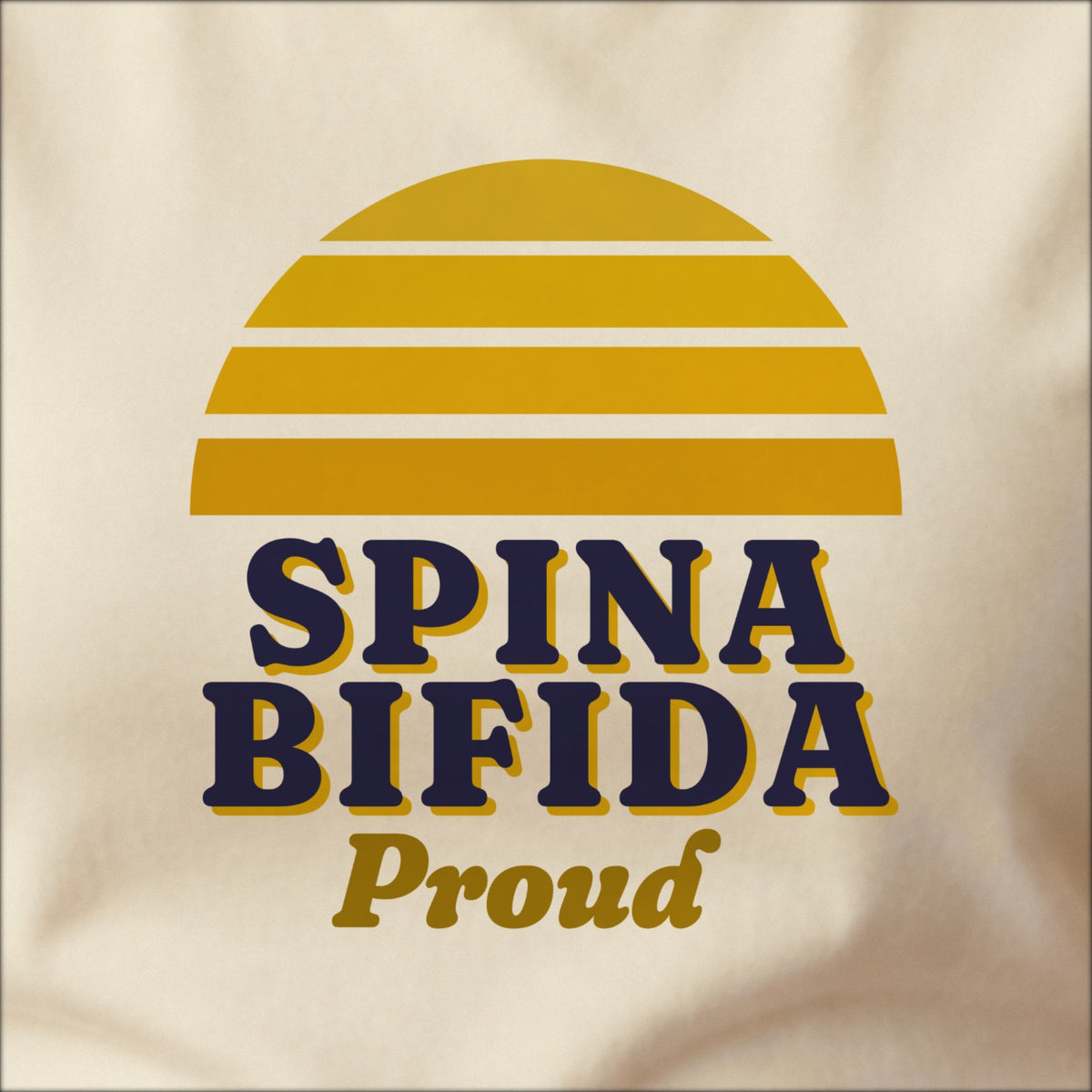 Close-up of the print on a natural tee: a striped half-sun in yellow above bold SPINA BIFIDA lettering with “Proud” in script.