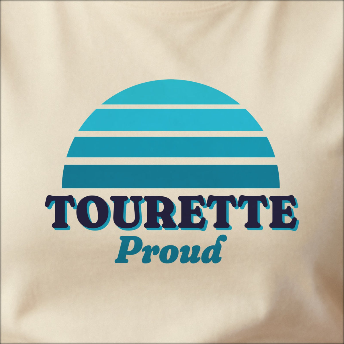 Close-up of the print on a natural tee: a striped half-sun in teal above bold TOURETTE lettering with “Proud” in script.